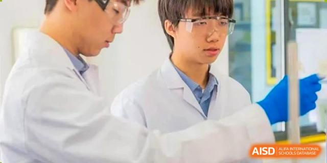 A focused Yew Wah International Education School of Yantai Campus student in protective eyewear and a lab coat during a science class.