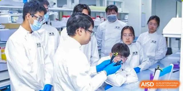 A Yew Wah International Education School of Yantai Campus teacher or older student in a lab coat performing a demonstration for a younger student.