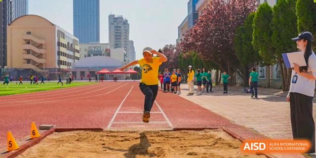 Yew Wah International Education School of Yantai Campus student performing a long jump at a track and field competition.