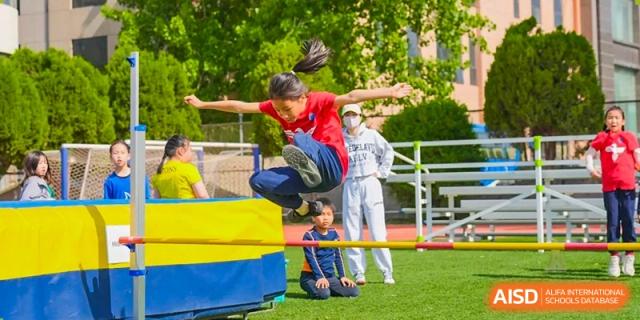 Yew Wah International Education School of Yantai Campus student participating in a high jump event during a school sports day.