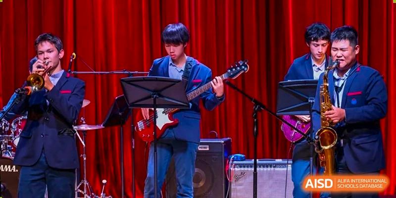Yew Wah International Education School of Yantai Campus student playing an electric guitar during a performance on a stage.