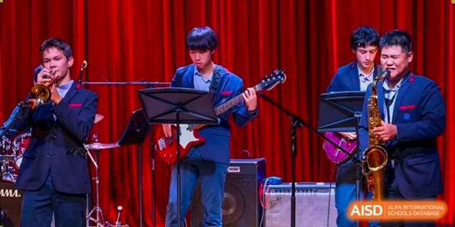 Yew Wah International Education School of Yantai Campus student playing an electric guitar during a performance on a stage.