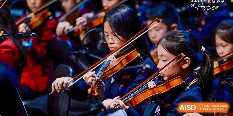 Students from Yew Wah International Education School of Yantai Campus playing the violin and other string instruments in an orchestra.