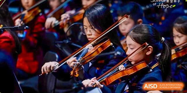 Students from Yew Wah International Education School of Yantai Campus playing the violin and other string instruments in an orchestra.