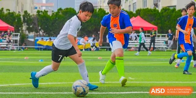 Young students from Yew Wah International Education School of Yantai Campus playing football (soccer) on an artificial turf field.