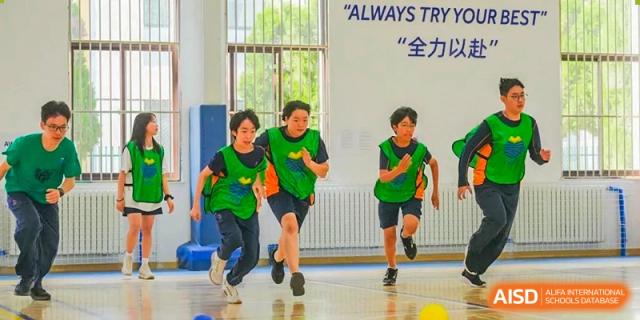 Yew Wah International Education School of Yantai Campus students running a race indoors during a physical education or sports event.
