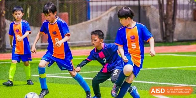 Two Yew Wah International Education School of Yantai Campus students competing for the ball during a football (soccer) game.