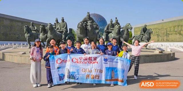 Yew Wah International Education School of Yantai Campus students posing with a banner during an educational field trip, possibly to an historical site in China.