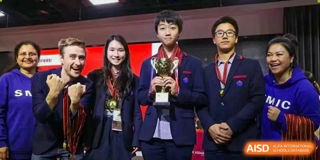 A proud Yew Wah International Education School of Yantai Campus student holding a trophy with a teacher or staff member after a competition.