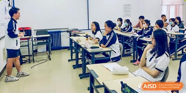 Students seated at individual desks in a classroom, focused on their work during a lesson, at Ulink College of Beijing.