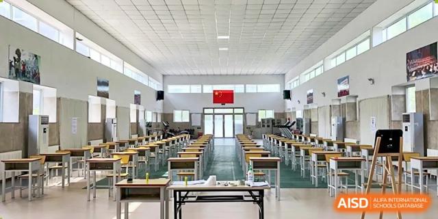 An interior view of a large, empty, brightly lit dining hall or multi-purpose room with tables and chairs neatly arranged, at Ulink College of Beijing.