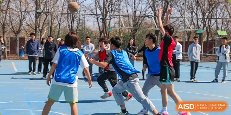 Students actively running and competing on an outdoor court during a sports game, showing dynamic movement, at Ulink College of Beijing.