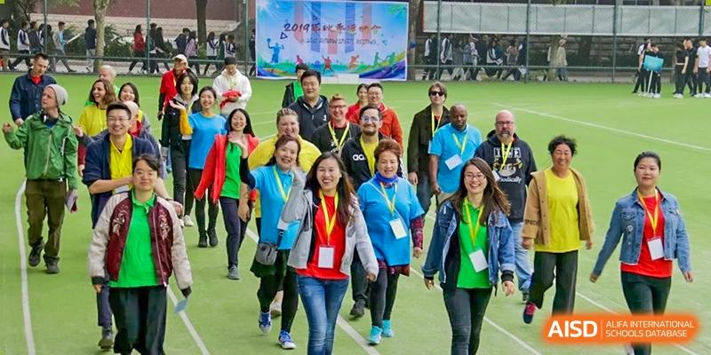 A large group of students and adults wearing medals and bright jackets walking together during a school event or activity, at Ulink College of Beijing.