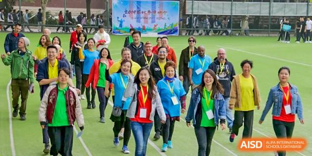 A large group of students and adults wearing medals and bright jackets walking together during a school event or activity, at Ulink College of Beijing.