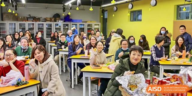 A large group of parents or adults seated at tables in a brightly lit room, attending a health or nutrition lecture or workshop, at Ulink College of Beijing.