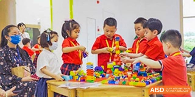 Young children in a brightly lit classroom playing and collaborating while building colorful structures with small building blocks at Sedbergh School Fuzhou.