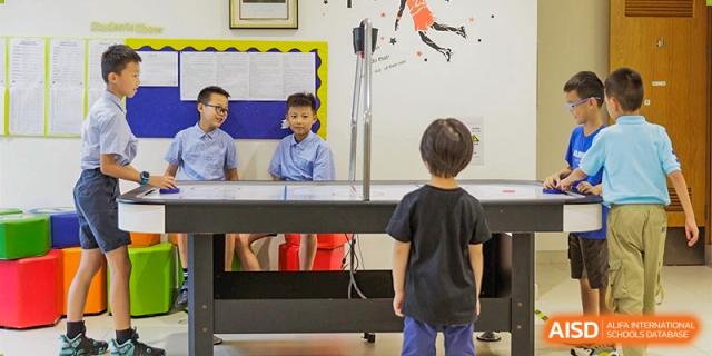A young student in a black shirt stands facing a large piece of scientific equipment, possibly a physics or engineering lab setup, at Sedbergh School Fuzhou.