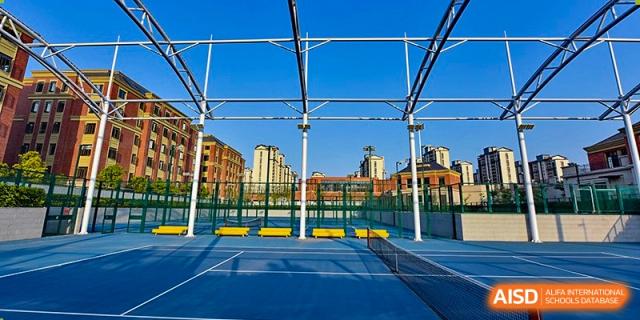 An outdoor tennis or multi-use sports court enclosed by blue fencing and netting on the campus of Sedbergh School Fuzhou.