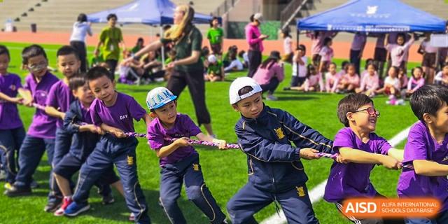 Older students wearing school uniforms competing in an intense tug-of-war match during a sports day at Sedbergh School Fuzhou.