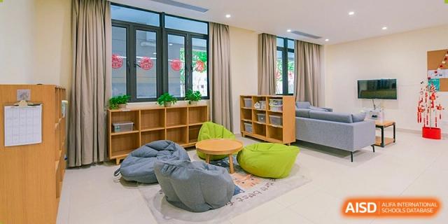 A bright, modern student lounge or reading corner with beanbag chairs and wooden shelving by a large window at Sedbergh School Fuzhou.