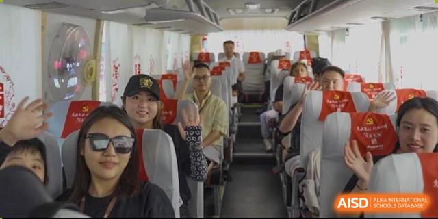 Students and teachers smiling while sitting inside a school bus or coach during a field trip or transportation at Sedbergh School Fuzhou.