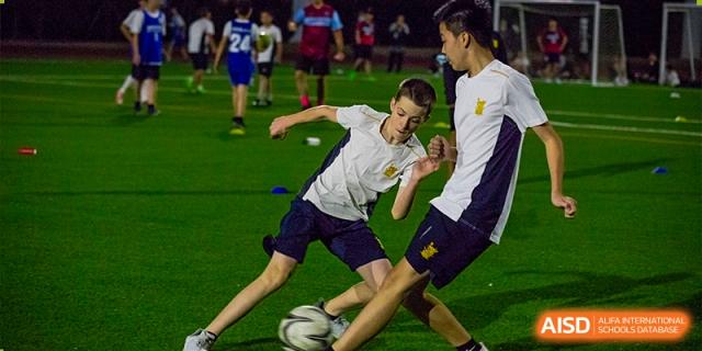 Two older students intensely competing for the ball during a nighttime soccer match on an illuminated pitch at Sedbergh School Fuzhou.