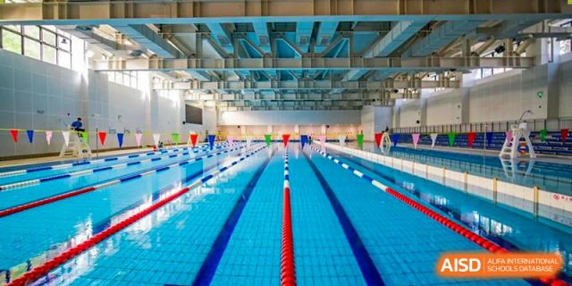 A wide interior view of the large, modern, brightly lit indoor swimming pool with multiple lanes at Sedbergh School Fuzhou.
