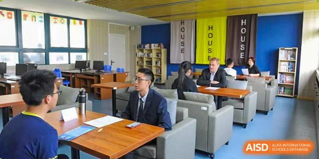 An indoor student lounge or study area at Wenzhou No.22 Senior Middle School, featuring comfortable gray seating, tables, and banners for "HOUSE YELLOW" and "HOUSE GRAY."