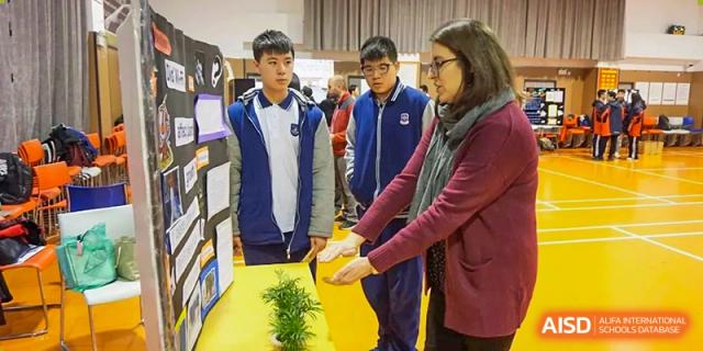Wenzhou No.22 Senior Middle School students interacting with a teacher or instructor while looking at materials in a study or library setting.