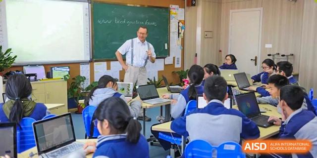 A teacher at Wenzhou No.22 Senior Middle School instructing students in a classroom, standing over them with arms out.