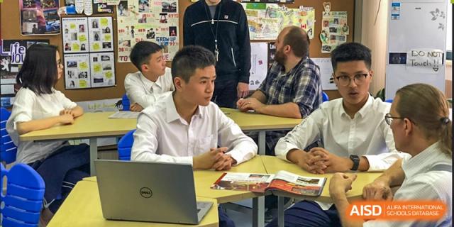 Wenzhou No.22 Senior Middle School students working on laptops and textbooks during a small group class session.