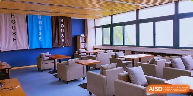 A bright and modern student common area at Wenzhou No.22 Senior Middle School, featuring lounge chairs, small tables, and large windows.
