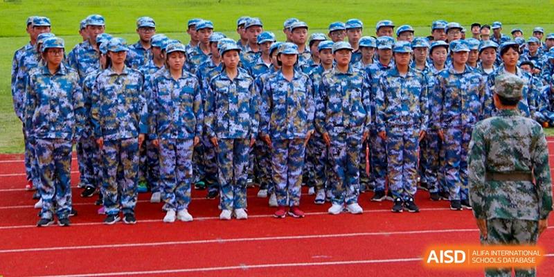 Large formation of Wenzhou No.22 Senior Middle School students standing on a red track in full camouflage military-style uniform during a training exercise or ceremony.