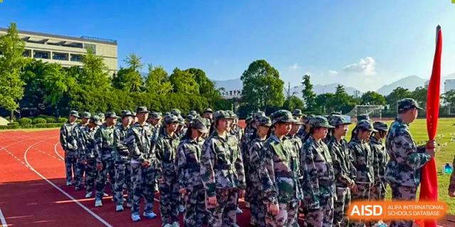 Large group of Wenzhou No.22 Senior Middle School students standing in formation in camouflage uniforms during a military training exercise or parade.