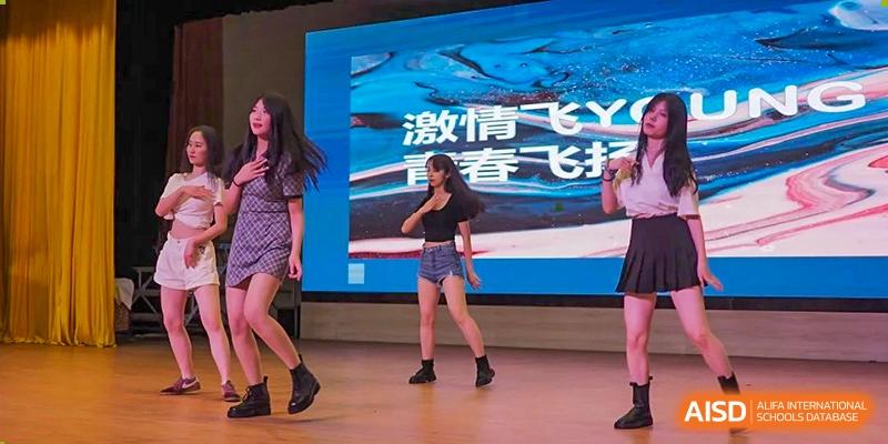 Wenzhou No.22 Senior Middle School students performing a lively modern dance routine on stage during a school event.