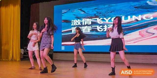 Wenzhou No.22 Senior Middle School students performing a lively modern dance routine on stage during a school event.