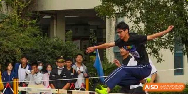 Wenzhou No.22 Senior Middle School students participating in a fun outdoor game or team challenge, focused on crossing a barrier or completing an obstacle.
