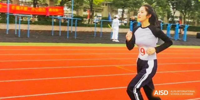 Wenzhou No.22 Senior Middle School student running on the red track during an outdoor track and field competition.