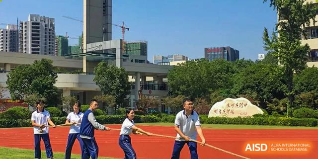 Wenzhou No.22 Senior Middle School students competing in a Tug-of-War event on the track field, with campus buildings in the background.