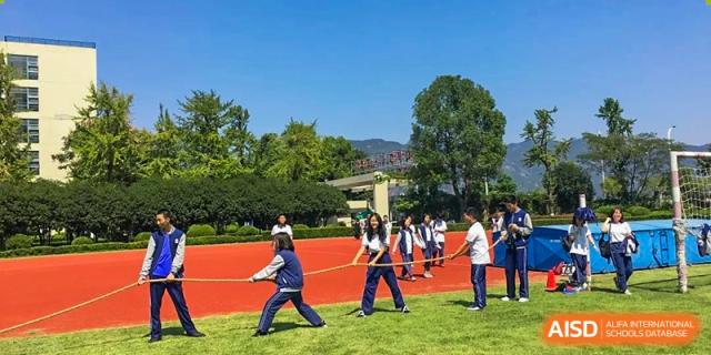Wenzhou No.22 Senior Middle School students participating in a Tug-of-War competition on a grassy field, with spectators watching.