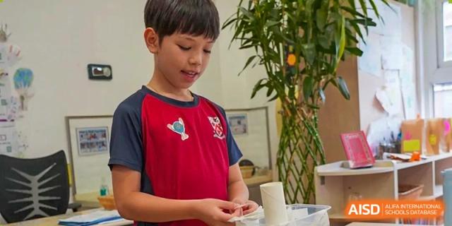 A young male student from Dulwich International High School Programme Hengqin (DHHQ) focused on a hands-on activity or project indoors.