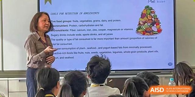 Students from Dulwich International High School Programme Hengqin (DHHQ) watching a projector screen with a presentation on "Tools for Nutrition" during a health or science lesson.