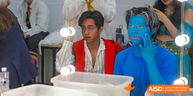 Two male students from Dulwich International High School Programme Hengqin (DHHQ) backstage or preparing for a drama or theatrical performance, with one student wearing blue body paint.