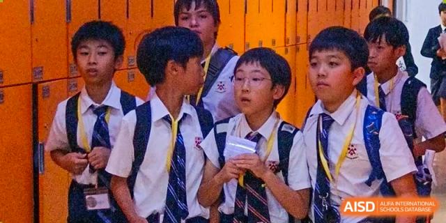A close-up of several male students from Dulwich International High School Programme Hengqin (DHHQ) in school uniform, engaged in a conversation or watching a presentation.