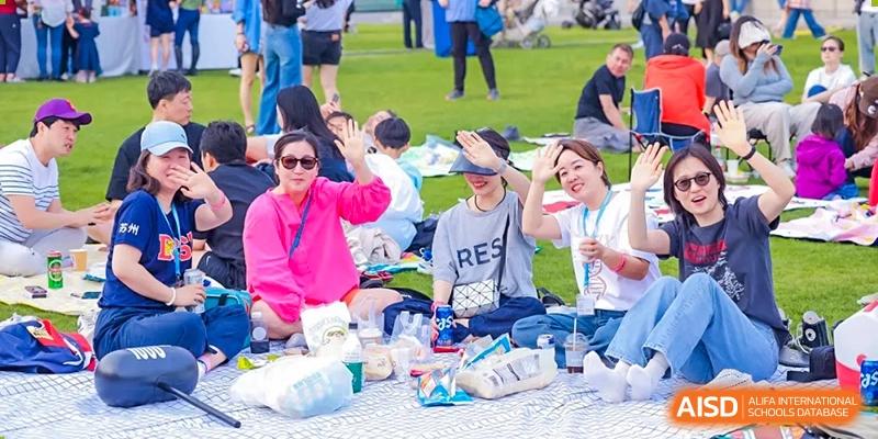 Parents and students from Dulwich International High School Programme Hengqin (DHHQ) relaxing and enjoying a picnic or outdoor event on the grass.