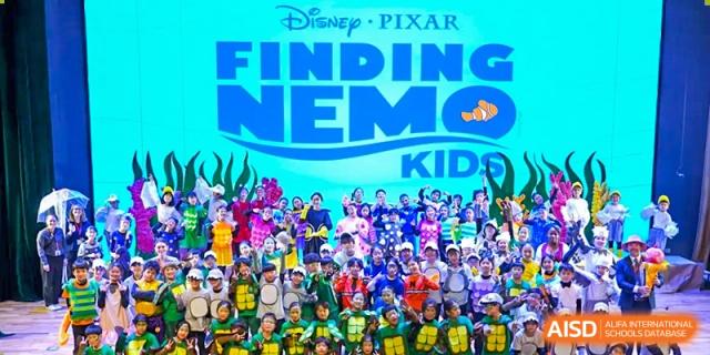 A large group of students from Dulwich International High School Programme Hengqin (DHHQ) posing together in front of a "Disney Pixar FINDING NEMO KIDS" banner, likely after a musical or production.