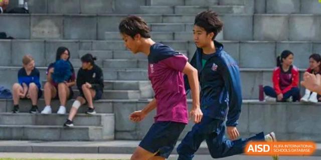 Two male students from Dulwich International High School Programme Hengqin (DHHQ) running up stairs or bleachers during a physical training session.