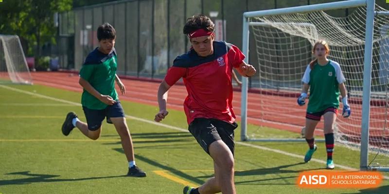 A male student from Dulwich International High School Programme Hengqin (DHHQ) running or sprinting on a sports field during a physical education class or competition.