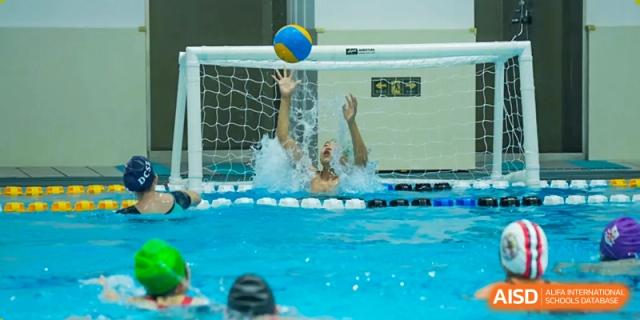 A water polo goalie from Dulwich International High School Programme Hengqin (DHHQ) attempting to block a shot in the pool.