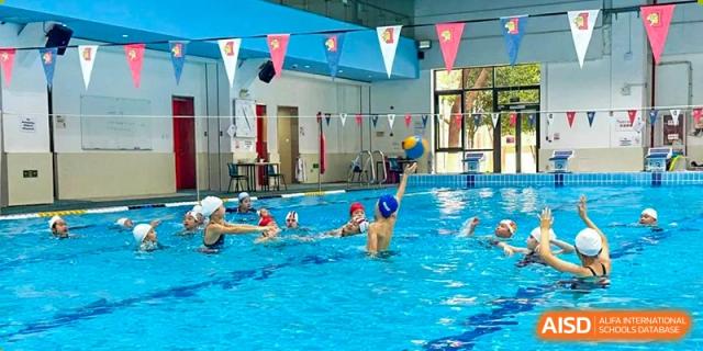 Students from Dulwich International High School Programme Hengqin (DHHQ) playing a water polo game in an indoor swimming pool.